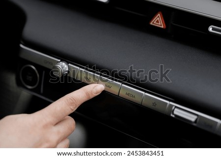 Close-up view of car interior. View of car navigation button. Driver pressing navigation button of electric car. GPS Navigation map system screen in the car for travel.
