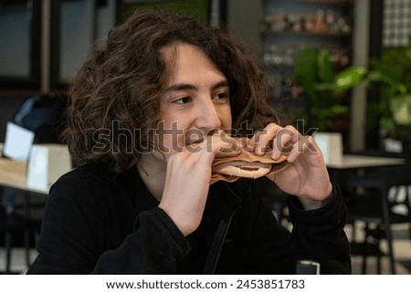 Long-haired boy eating toast in a cafe.
