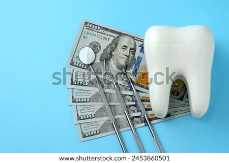 Dental Service, Insurance and dentist bill cost. The concept of saving money for dental treatment. Dollar money bills and tooth model on a bluebackgound with copy space
