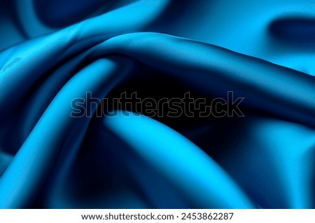 Wavy turquoise cyan translucent fabric in the sun, in folds. macro, blue crepe chiffon, texture.