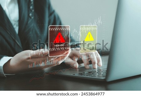 Businessman using smartphone and notebook at work desk with warning sign for caution in investment, warning of economic situation, risk in business investment.