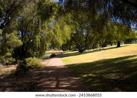 Scenic view of the cycle way and walk path near Central Lakes, Dalyellup, South Western Australia on a fine morning in late summer with shady trees and green lawns.