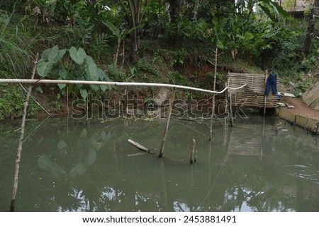 A traditional pond that usually found in the village. The bathing area are made from bamboo Royalty-Free Stock Photo #2453881491