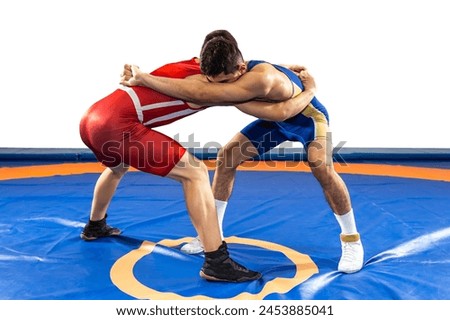 Two  strong men in blue and red wrestling tights are wrestling  on a white background. Wrestlers doing grapple. 
