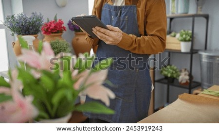 Hispanic man with beard uses tablet in flower shop surrounded by assorted plants, giving a modern entrepreneur vibe. Royalty-Free Stock Photo #2453919243