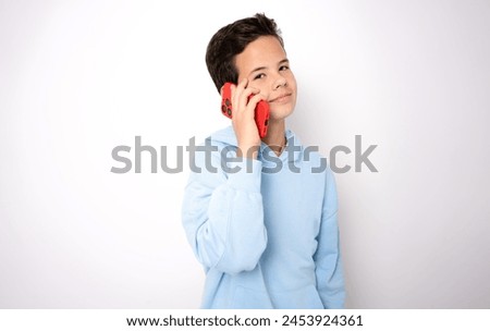 Young boy talking on smartphone standing isolated on white background.