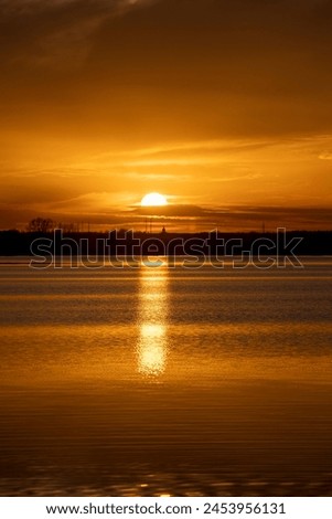 The sky and the lake are red-tinged during sunset, a beautiful sunset on the lake in early spring Royalty-Free Stock Photo #2453956131