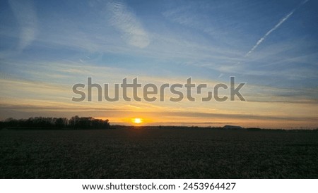 Sunset illuminates sky, casting warm hues over field and trees Mittellandkanal Wunstorf