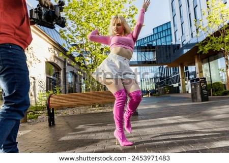 Behind The Scenes Photo With Young Female Vogue Dancer Performing Her Choreography On Modern City Street. Operator Filming Caucasian Woman Voguing With Professional High-Resolution Camera.