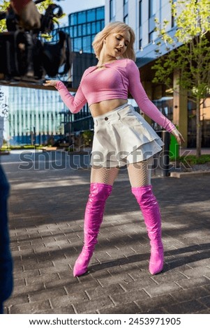 Vertical Screen: Behind The Scenes Photo With Young Female Vogue Dancer Performing Her Choreography On Modern City Street. Operator Filming Caucasian Woman Voguing With Professional Camera.