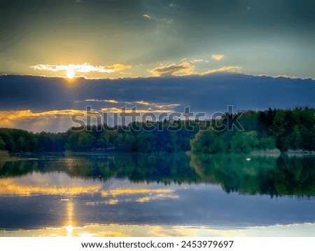 Serene Fishing Lake: A peaceful scene by the tranquil waters of a secluded fishing lake. Surrounded by lush greenery and framed by a clear blue sky, this picture captures the essence of a perfect day 