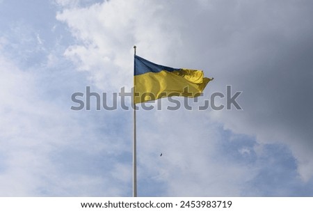 Ukrainian flag is symbol of the country. Ukraine will be forever! Windy view of large flag in two colors. Blue and yellow big flag in the wind. Cloudy sky is beautiful background. Independence day be!