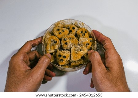 Peanut cookies are served in round packaging with a plain white background, and are held in two hands, right and left