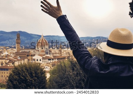 Happy young woman wearing hat , with arms raised at Florence panorama view.