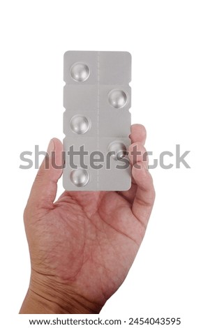 Hand holding silver strip packs of pills isolated on white background.