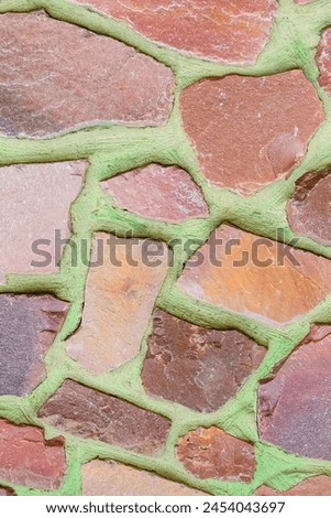 It is photo of colorful stones on green background. Its close up of multicolored stone wall of building. It is the photo of mosaic tile floor
