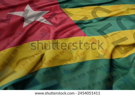 waving colorful national flag of togo on a euro money banknotes background. finance concept. macro shot