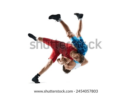 Two greco-roman wrestlers in red and blue uniform wrestling isolated on white background. Competitive young men. Concept of combat sport, martial arts, competition, tournament, athleticism Royalty-Free Stock Photo #2454057803