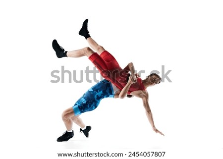 Two male athletes engage in wrestling match, grappling and striving for dominance isolated on white background. Concept of combat sport, martial arts, competition, tournament, athleticism