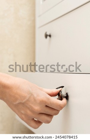 woman opens a cabinet drawer using the handle. woman opens cabinet drawer. vertical photo