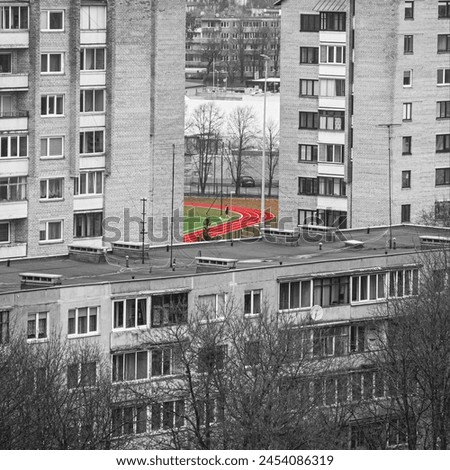 Picture of a guy playing football in the middle of soviet style apartments. Colour selection