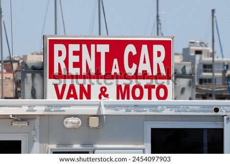 sign that says : rent a car , van and moto, with red and white letters . sunny day