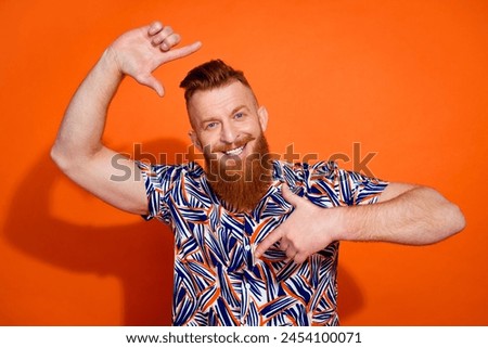 Photo of funky positive guy dressed print shirt showing fingers photo gesture isolated orange color background