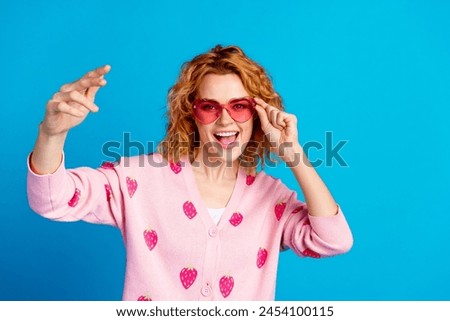Photo portrait of lovely young lady touch sunglass have fun dressed stylish pink clothes isolated on blue color background
