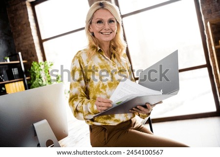 Photo portrait of lovely mature woman hold folder read documents dressed stylish shirt office day light home interior workspace
