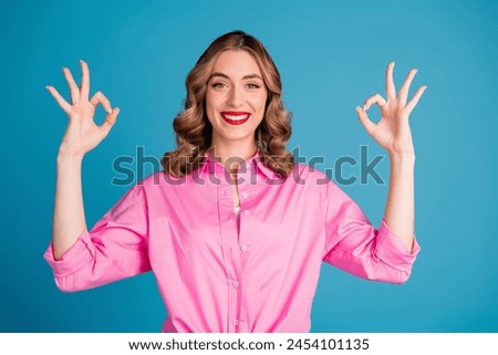Photo portrait of pretty young girl show okey gesture wear trendy pink outfit hairdo isolated on blue color background