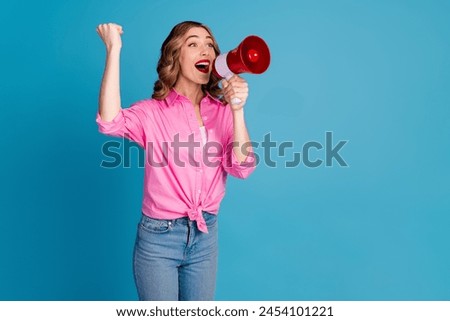 Photo portrait of pretty young girl raise fist hold megaphone wear trendy pink outfit hairdo isolated on blue color background