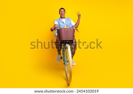 Full size photo of multiethnic multinational man dressed denim vest riding cycle show v-sign isolated on vibrant yellow color background Royalty-Free Stock Photo #2454102019