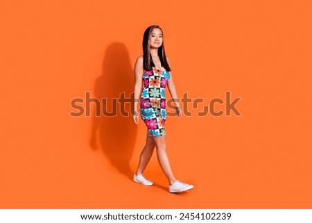 Full length photo of positive adorable woman dressed flower print clothes go shopping empty space isolated on orange color background