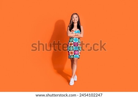 Full size photo of gorgeous lovely positive woman wear print stylish dress holding arms crossed isolated on orange color background