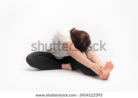 Woman does gymnastics and performs an exercise to develop flexibility. Portrait of girl practicing yoga on white background