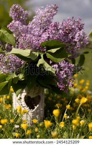 Bouquet of lilacs in a wicker vase standing in nature in the grass. High quality photo