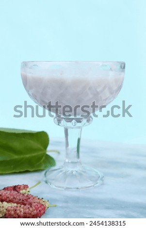 Juice glass of mulberry with green leaf and mulberry isolated on green background. Concept isolate pictures.