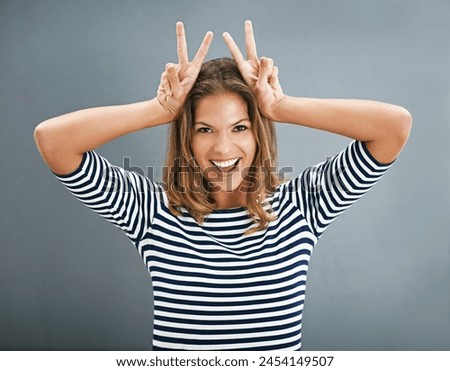 Woman, bunny ears and fingers in studio portrait, funny sign and play on gray background. Female person, emoji and rabbit icon or symbol for comedy, comic gesture and mockup space for easter humor