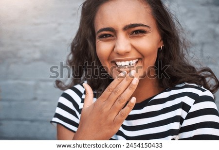 Woman, portrait and giggling with hand, joke and laugh for funny joke or meme on grey background. Girl, brick wall and urban fashion for comic, comedy and downtown with playful confidence and fun