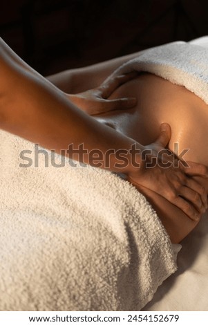 Hands massaging a woman's stomach. Therapist presses on the stomach. Woman getting a massage at a spa. Vertical photo