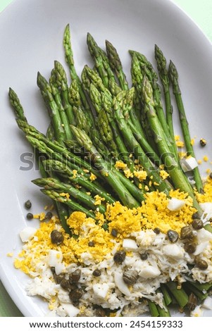 Asparagus salad Mimosa. Spring and Easter salad with grated egg, capers and aromatic dressing. Mint background. Healthy vegetarian balanced recipes for spring, seasonal cuisine, close up