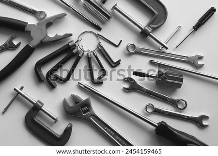Chaotically scattered hand tools on a white shelf. Monochrome stock photo for repairing backgrounds
