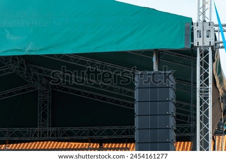 Large indoor outdoor stage for concerts. Professional sound and lighting equipment on stage. Monitor speakers  and big screen on stage.