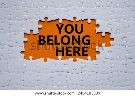You belong here symbol. White puzzle with words You belong here. Beautiful orange background. Business and You belong here setbacks concept. Copy space.