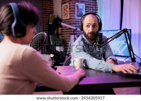 Show presenter interviewing designer during live stream, talking about fashion and style trends. Man having conversation with social media influencer, recording episode for podcast Royalty-Free Stock Photo #2454205917
