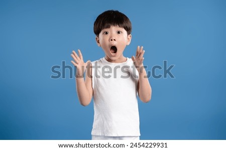 Portrait of asian kid boy wearing tank top and posing on blue background
