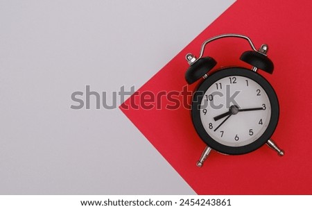 A black alarm clock sitting on top of a red background