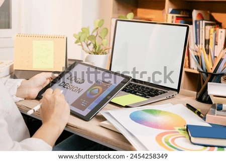 Designer at work on a table, selecting color shades for creative graphic design with laptop and tablet