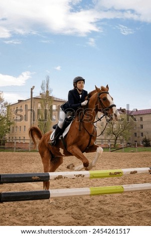 Rider jumping horse over obstacle, equestrian sport. Riding session. Female jockey in uniform riding equine. Show jumping. Horseback riding school Royalty-Free Stock Photo #2454261517