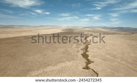 Water flows through the desert. River in a desert area view from the top. A life-giving river in the desert. The source of life is in the sands. View from the top of the desert.